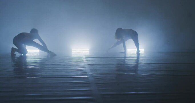 Couple preforming art or contemporary dance in room filled with smoke