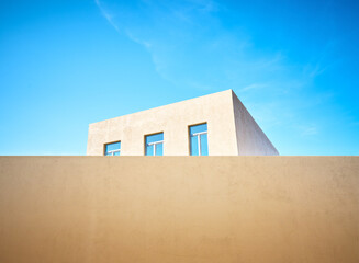 House with blue Windows behind a fence against the sky