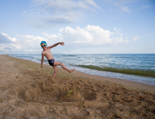 Happy child plays on the seashore with sand. Copy space. 