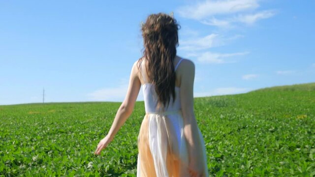 Sexy girl running on a green field. Beautiful happy model walks on a green meadow. Summer, field, blue sky.