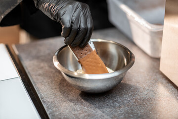 Chef making chocolate ice cream with toppings at the shop, close-up