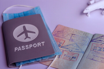 Fototapeta premium Passport with surgical mask, airplane and small suitcase placed on white background. Lifestyle and traveling concept.