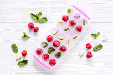 Naklejka na ściany i meble Ice tray with berries, lime and mint on white background top view