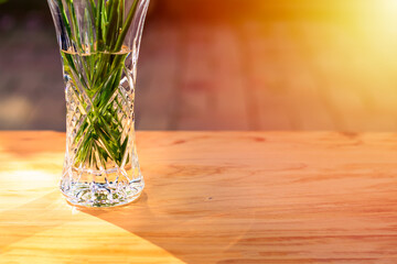 Sunlight reflacts in a crystal vase with flowers standing on a wooden table