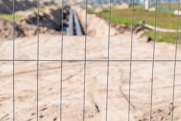 construction work, foundation pit with pipes, fenced, blurry background, focus to the foreground