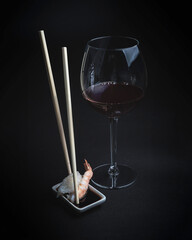 Sushi with red wine on a dark restaurant background. Chopsticks. A glass of wine. Soy sauce. Rolls and sushi. Japanese cuisine.
