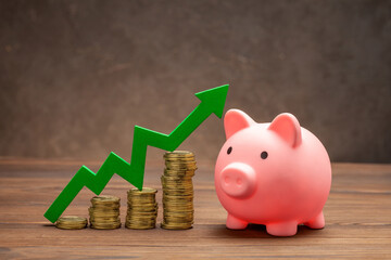 Piggy bank with coins and green arrow up. Concept of growth in savings