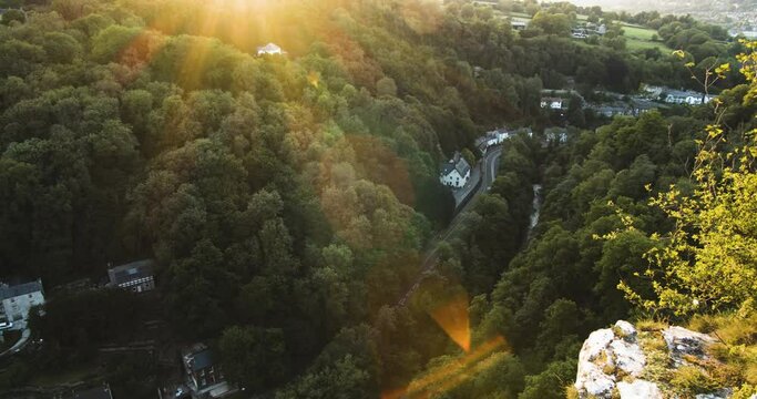 Aerial view of a small road winding through the dense forest of the Derbyshire countryside.