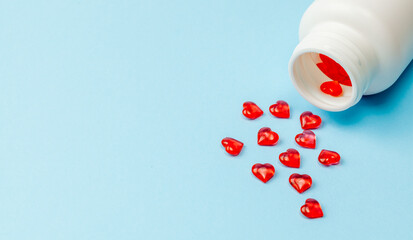 Pills of love. Red pills in the shape of heart with bottle on blue background. Copy space for text