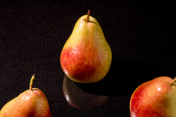 Three pears on a black background with hatching, closeup