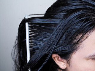Close-up on head of Asian people have long black hair, combing hair with hairbrush. 