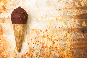 Cono de helado de chocolate sobre un fondo marrón grunge. Vista superior y de cerca. Copy space - obrazy, fototapety, plakaty