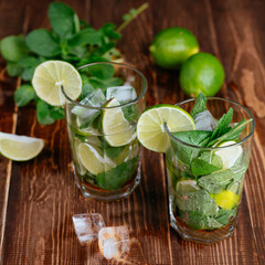mojito cocktail with lime and mint on wooden background