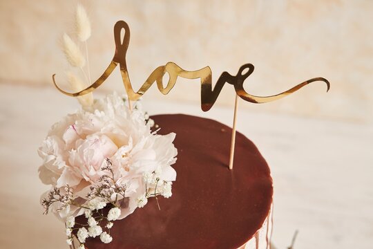 Delicious Wedding cake with chocolate drip and love topper on a white table with white background