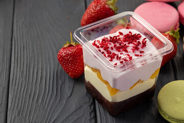Mousse dessert in plastic transparent box on black wooden table