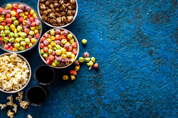Set of flavored popcorn and soda on blue table top view copy space
