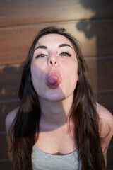 Young woman shows tongue on background of brown wall in street