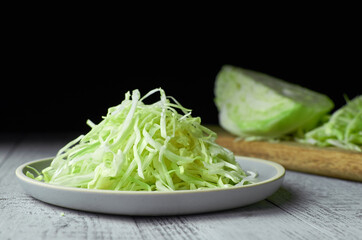 Shredded cabbage salad on ceramic plate over wooden background.