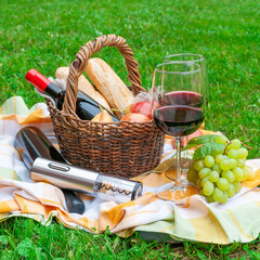An electric corkscrew lies on a bottle of wine. Nearby are two glasses of wine and a bunch of...