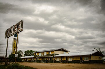 Rusty metal motel sign with wooden old motels under the cloudy and rainy  sky