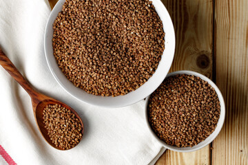 Bowl of raw uncooked buckwheat on wooden table