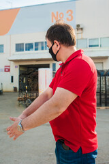 Fototapeta premium A man in a black mask and a red shirt is standing at a construction warehouse outside. Construction concept