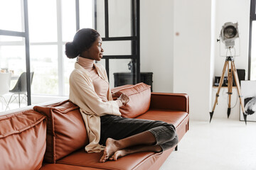 Attractive young smiling african woman sitting on a couch