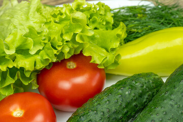 beautiful fresh, juicy vegetables on a white plate: fresh peppers, tomatoes, cucumbers, lettuce, dill
