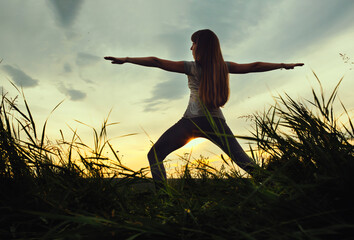Woman doing yoga fitness exercise outdoor landscape. Evening sunset, meditation and relax