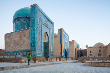 Woman tourist stands near the ancient building in the city of Samarkand in Uzbekistan at sunrise