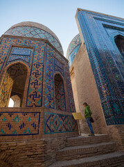 Woman tourist stands near the ancient building in the city of Samarkand in Uzbekistan and reads sign