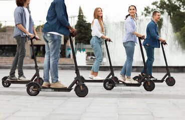 Friends having pleasant ride on motorized kick scooters © Prostock-studio