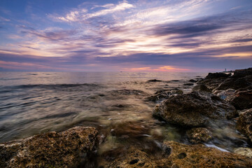 Obraz premium Dramatic sunset over beach with a natural pond in the foreground.