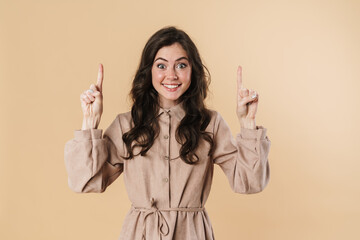 Image of cheerful attractive woman smiling and pointing fingers upward
