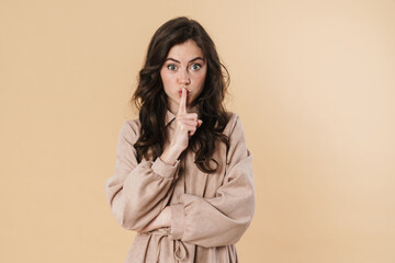 Image of surprised woman showing silence gesture and looking at camera