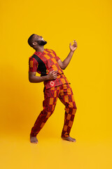 Joyful african man fooling over yellow background