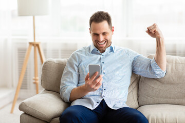 Excited adult man feeling ecstatic holding phone
