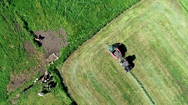 Treker mit einer roten Stroh Festkammerpresse bei der Strohernte auf einem gem&auml;hten Feld