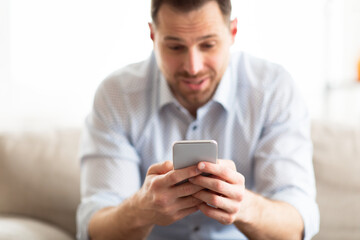 Obraz na płótnie Canvas Handsome adult man using smart phone at home