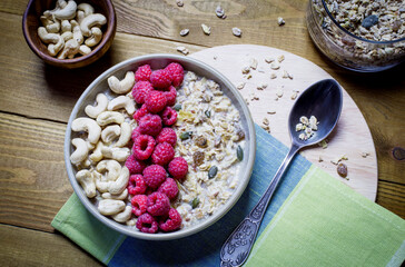 Healthy Breakfast with muesli, cashew nuts and fresh raspberries on a wooden background. Copy space