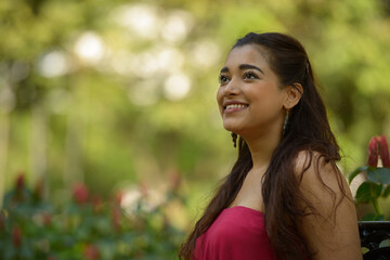 Face of happy young beautiful Indian woman thinking at the park