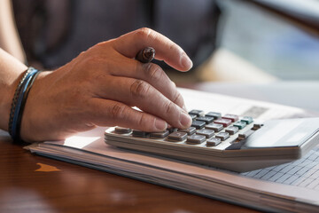 Man's finger press on plus button calculator.