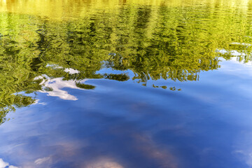 Fototapeta na wymiar Wavy water surface of the river with reflection of coastal vegetation