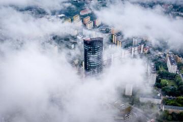 Aerial view from top on skyscraper Sky Tower in the fog in Wroclaw. Epic foggy morning in the city and tall building in the clouds. Wroclaw, Poland
