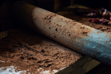 Grinding cacao beans with chili peppers to make chocolate by stone rolling pin on stone surface....