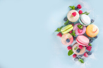 Colorful french macaron dessert. Set of various different tastes and color macaron cookies with berries, sugar powder and mint on blue background