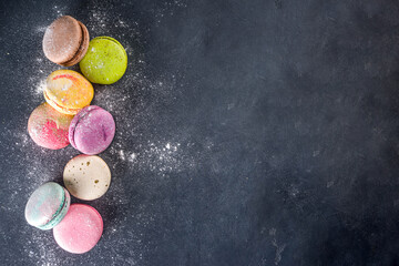 Fototapeta na wymiar Colorful french macaron dessert. Set of various different tastes and color macaron cookies with berries, sugar powder and mint on dark grey stone background