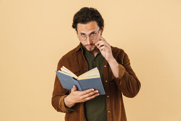 Image of serious unshaven man in eyeglasses reading book