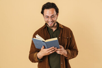 Image of joyful unshaven man in eyeglasses reading book and smiling
