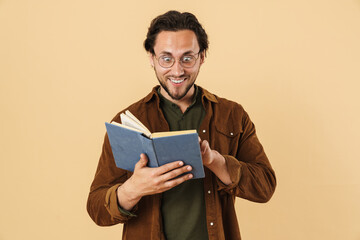 Image of excited unshaven man in eyeglasses reading book and smiling
